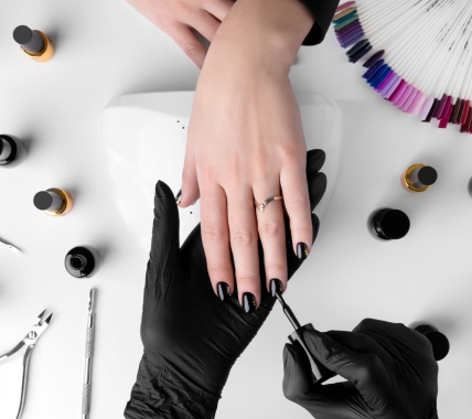 Woman making manicure in beauty salon. Professional tools and nail polish on white table. Hands care concept